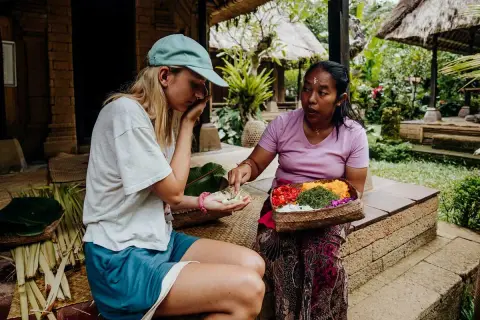 Une touriste apprend à faire des offrandes avec sa guide à Bali.