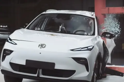 Białe chinskie auto MG po teście zderzeniowym Euro NCAP, z rozbitą szybą i uszkodzonymi elementami.