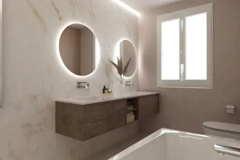 Bagni eleganti con pareti in marmo, doppio lavabo con specchi rotondi illuminati, mobile sospeso in legno e vasca da bagno.