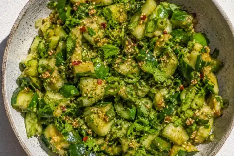 En skål med en matig sallad av gurka, örter och sesamfrön.