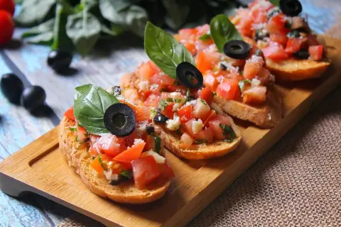 Bruschettas appétissantes avec tomates fraîches, basilic et olives noires sur du pain grillé. Un délice de pain bruschetta.
