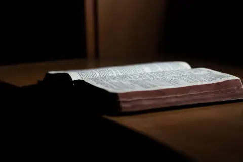 En öppen bibel ligger på ett träbord. Sidorna är fyllda med text, och det ser ut som om det är ett av breven som skrevs Paulus brev till.