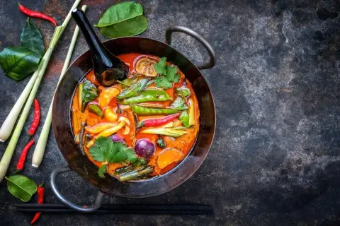 Kolorowe warzywa do curry: groszek cukrowy, papryczki chili, cebula, marchewka i trawa cytrynowa w aromatycznym sosie.