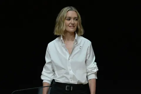 Marta Ortega Pérez, con una camisa blanca y un micrófono, sonríe ante la cámara.