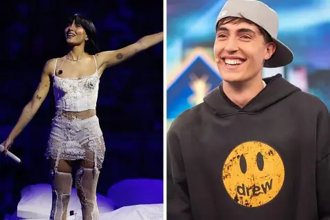 Aitana canta en el escenario con un traje blanco y su novio, Sebastián Yatra, sonríe con una gorra gris.