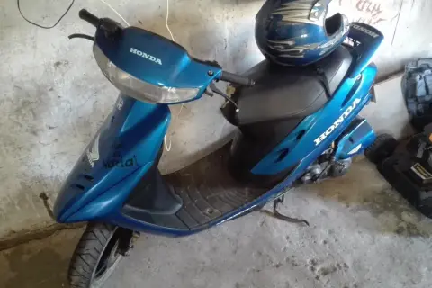 Niebieski skuter Honda Dio z niebieskim kaskiem ozdobionym płomieniami.