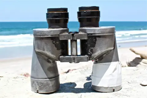 Binocolo sulla spiaggia, pronto a scrutare l'orizzonte. A cosa serve il binocolo? A vedere lontano, a scoprire dettagli nascosti nel paesaggio marino.