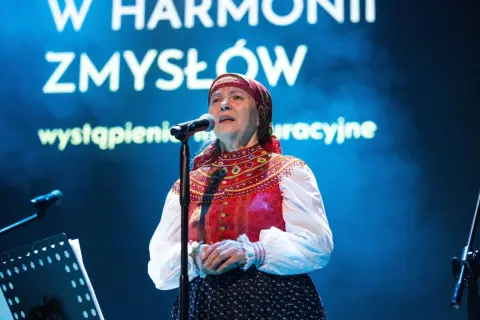 Julia Doszna w tradycyjnym stroju, śpiewająca na scenie.