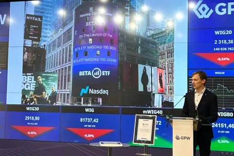 Prezentacja na GPW z informacjami o ETFach, w tym o BETA ETF NASDAQ-100. W tle widać ekrany z danymi giełdowymi.