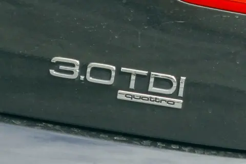 Napis "3.0 TDI quattro" na ciemnym lakierze samochodu. Informuje o pojemności silnika 3.0 litra i napędzie quattro.