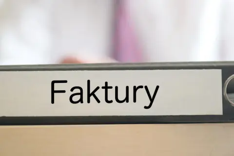 Segregator z napisem "Faktury" na biurku, gotowy do uporządkowania dokumentacji.