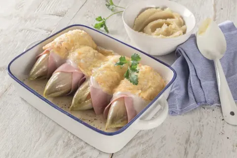 Endives au jambon gratinées, un plat classique dont l'origine est souvent attribuée à Bruxelles. Servi avec une purée onctueuse.