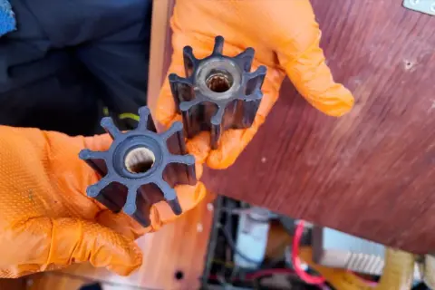 Mani con guanti arancioni mostrano giranti di una pompa, simili a quelle usate per capire come funziona un motore diesel.