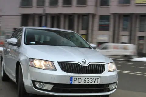 Srebrna Skoda Octavia 1.6 TDI jedzie ulicą miasta.