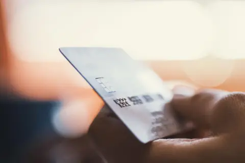 Dłoń trzyma kartę płatniczą. Zastanawiasz się, moneyback co to? To zwrot części pieniędzy za zakupy.