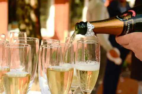 Nalewanie złotego **brut wino** do kieliszków. Bąbelki unoszą się, zapowiadając celebrację.