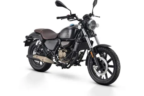 Czarny motocykl w stylu retro, z brązowym siedzeniem i złotymi elementami silnika. To najmocniejsze 125 na b, gotowe na każdą drogę.