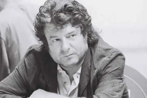 Enrique Morente joven, con su melena rizada y mirada pensativa, viste chaqueta de rayas.