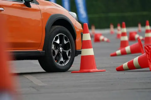 Pomarańczowy samochód na placu manewrowym, przygotowany do egzaminu na prawo jazdy nowe.