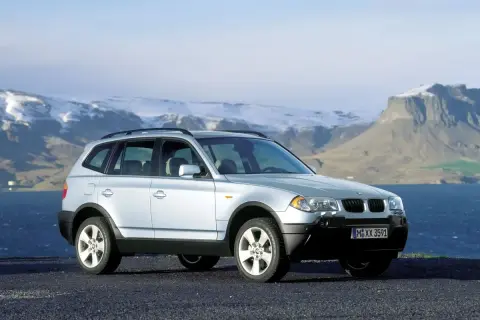 Srebrny BMW X3 E83 na tle gór i morza.