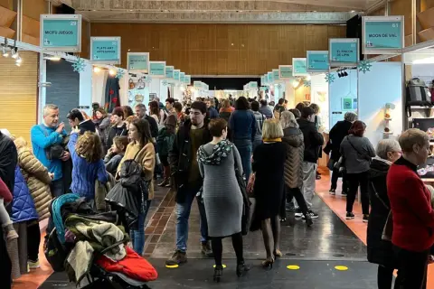 Gente disfrutando de la feria artesanía Zaragoza, con puestos de juegos, arte y bolsos.