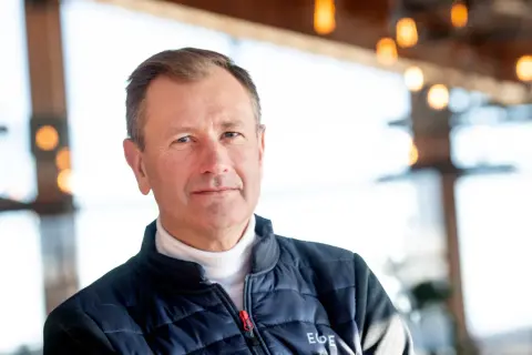 SkiStar VD, Stefan Söderberg, bär en blå dunjacka över en vit polotröja. Bakgrunden är suddig med ljus och trädetaljer.