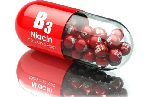 Czerwona kapsułka wypełniona małymi kulkami z napisem "Niacin B3". To niacynobaza w pigułce.