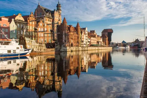 Gdańska starówka z żaglowcem i statkiem wycieczkowym, idealne instagramowe miejsca Gdańsk. Odbicia budynków w wodzie tworzą magiczny widok.