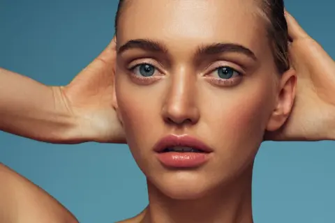 Rostro de mujer con piel radiante y labios jugosos. El retinol ayuda a renovar la piel, revelando su luminosidad natural.