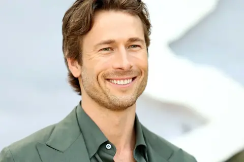 Lachender Glen Powell in grünem Anzug, bereit für neue Filme.