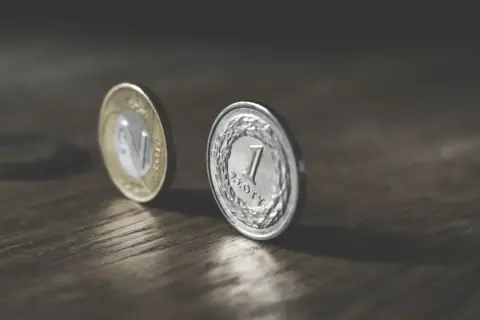 Monety na drewnianym blacie. Zastanawiasz się, ile to netto, gdy zarabiasz 6500 zł brutto?