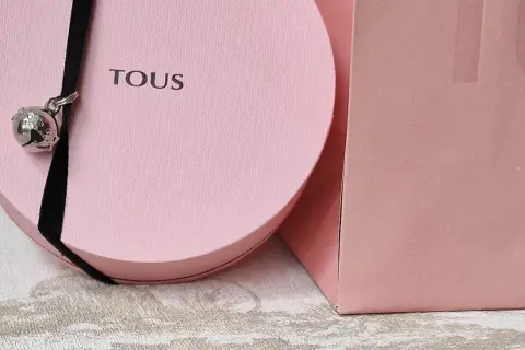 Caja rosa Tous con un charm de oso plateado colgando de un cordón negro. Ideal para tus colgantes Tous.