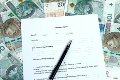 Umowa pożyczki na tle polskich banknotów. Szukasz informacji, gdzie pożyczki dla zadłużonych są dostępne? Dokument i pieniądze sugerują rozwiązanie.