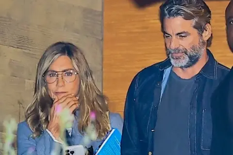 Jennifer Aniston w okularach i mężczyzna z siwą brodą.