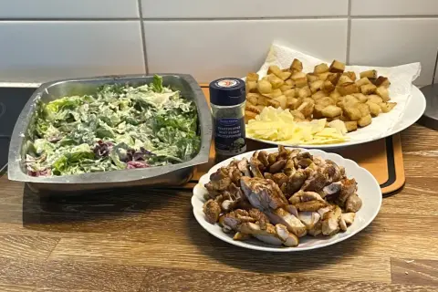 Förberedelser för ett fantastiskt ceasarsallad recept: krispig sallad, stekt kyckling, krutonger och parmesan.