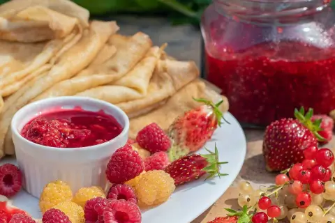 Färska hallon, jordgubbar och vinbär till ett härligt hallonsylt recept. Pannkakor och sylt i en härlig sommardukning.