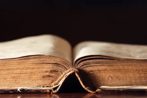 Stary, pożółkły tom księgi otwarty na środku, przypominający o tym, kiedy powstał Stary Testament.