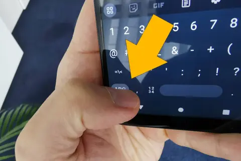 Żółta strzałka wskazuje na klawiaturę telefonu, na znak "<".