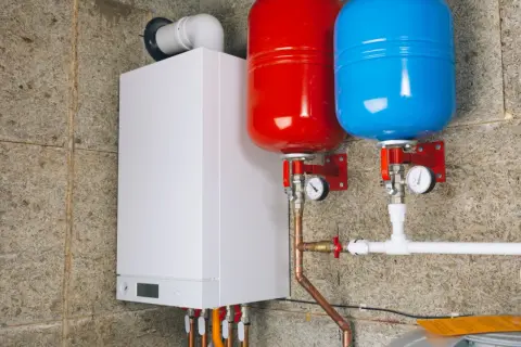 Chaudière blanche avec deux réservoirs de couleur rouge et bleue, un vase d'expansion essentiel pour le bon fonctionnement du système de chauffage.