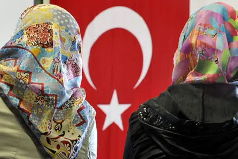 Zwei Frauen mit bunten Kopftüchern vor türkischer Flagge. Ein Bild von multikulti Deutschland.