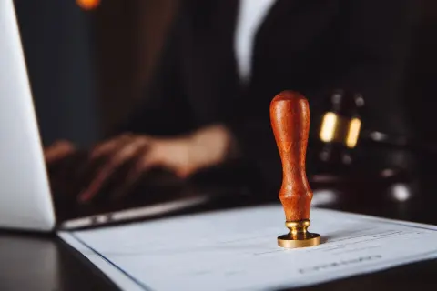 Pieczęć urzędowa na dokumencie, obok laptopa i młotka sędziowskiego. Rozważane są akcje pracownicze PKP po śmierci.