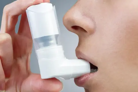 Dłoń trzyma inhalator Ventolin przy ustach. Szybka pomoc w trudnych chwilach.