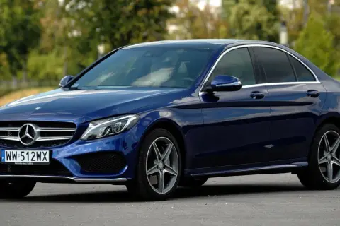 Granatowy Mercedes Klasy C, idealny do poznania jego **mercedes c klasa dane techniczne**. Elegancki sedan na tle zieleni.