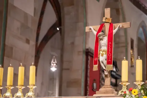 Chrystus na krzyżu z czerwoną wstęgą "Alleluja". Obok płonące świece. 25 marca święto kościelne.