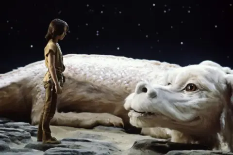Chłopiec Atreyu i biały smok Falkor, bohaterowie "Niekończącej się historii" Michaela Ende, patrzą na siebie pod rozgwieżdżonym niebem.