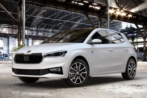 Biała Skoda Fabia Monte Carlo z czarnym dachem i felgami stoi w opuszczonej hali przemysłowej z graffiti.