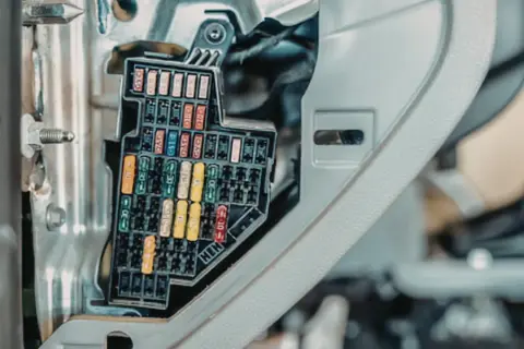Panel z bezpiecznikami, gdzie są bezpieczniki w skuterze. Różnokolorowe bezpieczniki w skrzynce.