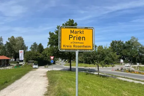 Schild "Markt Prien a.Chiemsee, Kreis Rosenheim" am Ortseingang. Heute ist ein sonniger Tag für den Markt.