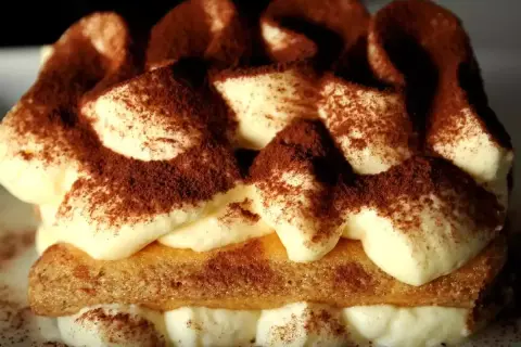 Un délicieux tiramisu au marsala, garni de cacao, avec des couches de crème onctueuse et de biscuits savoyards.