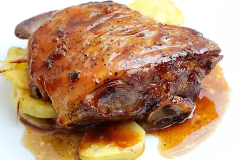 Ternasco asado jugoso y dorado, servido sobre patatas. ¡La mejor opción donde comer ternasco en Zaragoza!